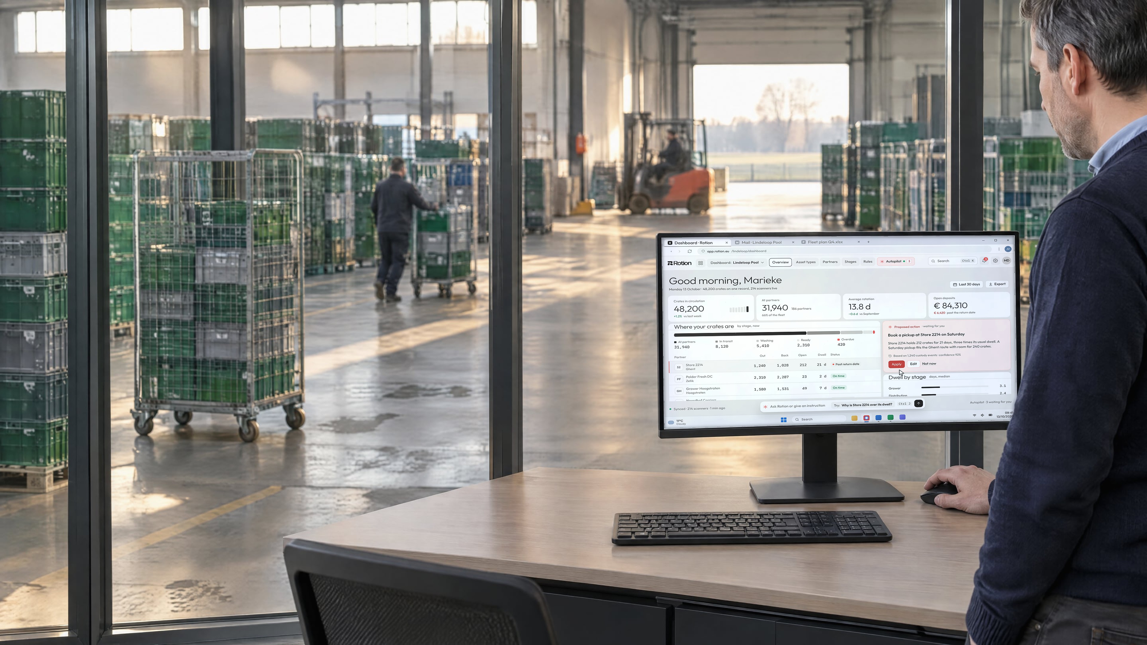 An operations manager at a desk beside a cross-dock, the monitor showing the Rotion dashboard with crates per stage and a pickup proposal from Autopilot